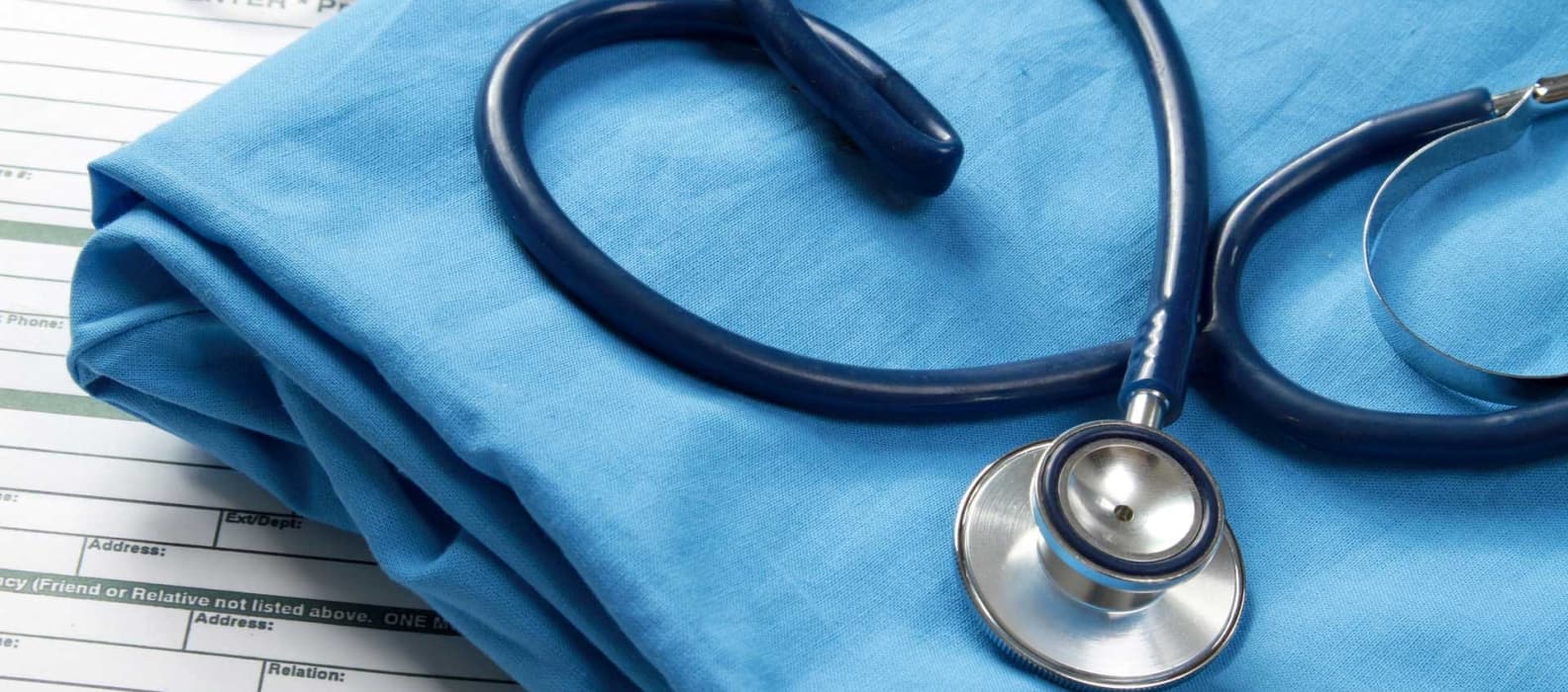 A stethoscope and folded scrubs resting on a patient intake form
